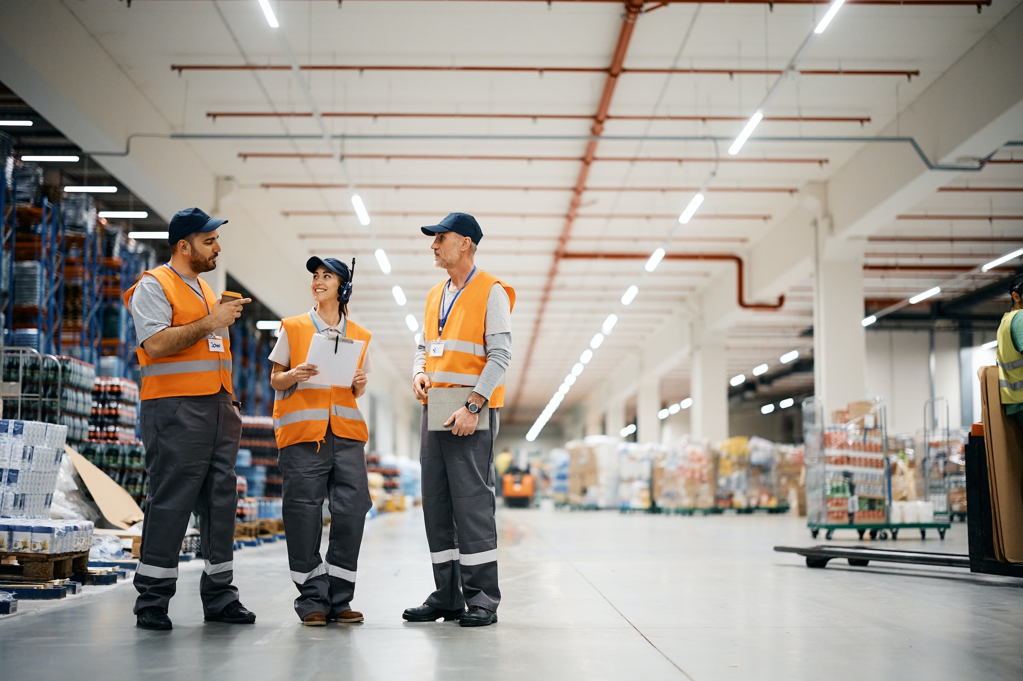 Group of happy workers talking while working at distribution warehouse.